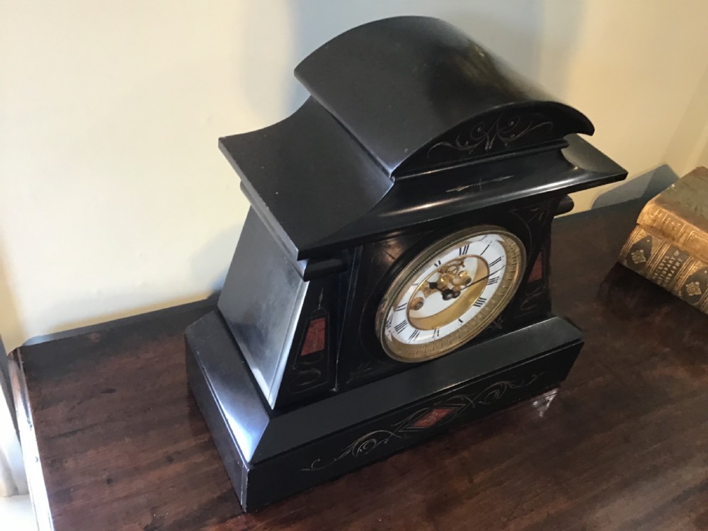 A black antique mantel clock featuring a white circular dial with Roman numerals, an exposed escapement, and gold scrollwork detailing across the case. View II