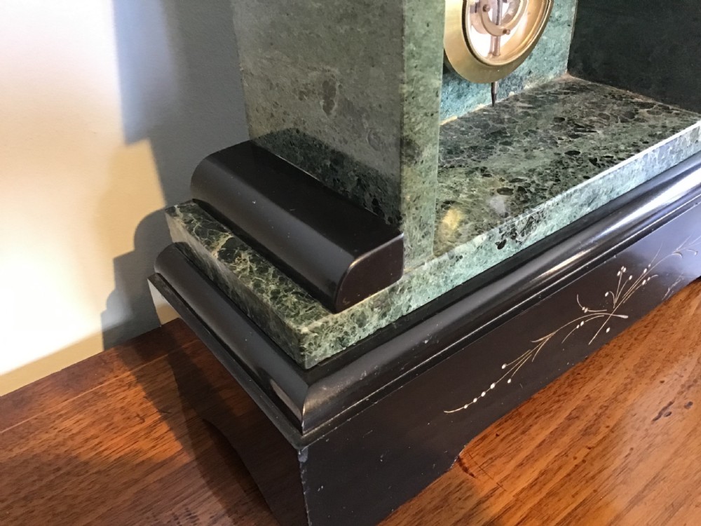 A Victorian black slate and green marble mantel clock featuring a white dial with a visible escapement and a brass pendulum. View VI