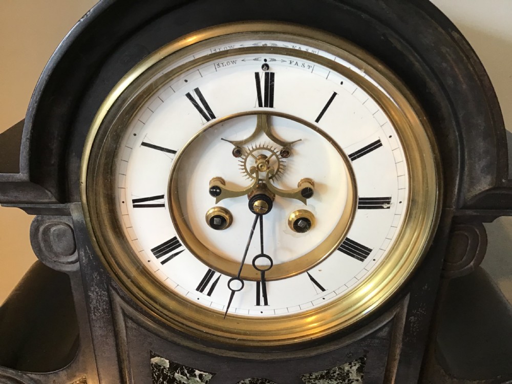 A Victorian black slate mantel clock featuring green marble inlays, scrolled side volutes, and a white enamel dial with an exposed escapement. View II
