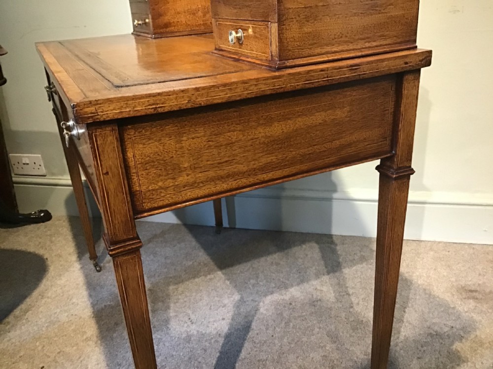 An antique mahogany writing desk featuring a central leather surface, a raised superstructure with stationery compartments, two frieze drawers, and tapered legs on brass castors. View IX