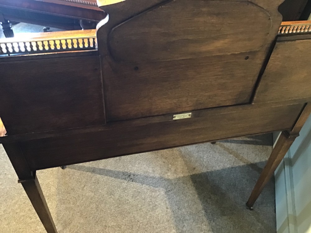 An antique mahogany writing desk featuring a central leather surface, a raised superstructure with stationery compartments, two frieze drawers, and tapered legs on brass castors. View XI