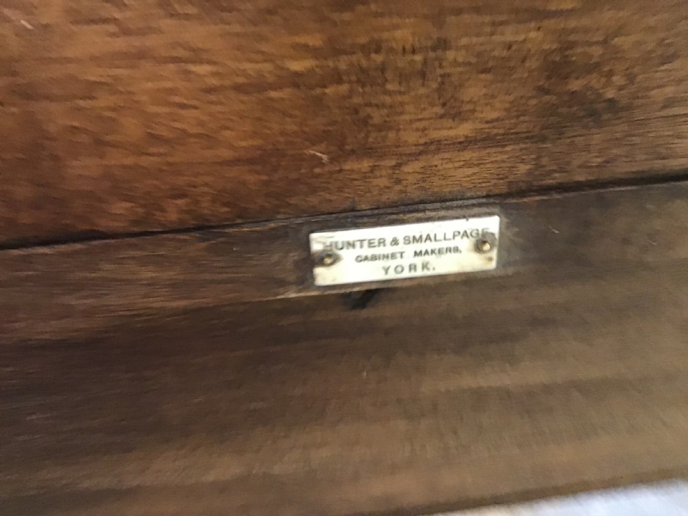 An antique mahogany writing desk featuring a central leather surface, a raised superstructure with stationery compartments, two frieze drawers, and tapered legs on brass castors. View XII