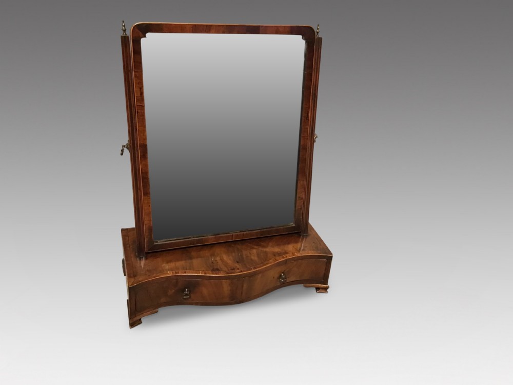 A Georgian mahogany toilet mirror featuring an adjustable glass plate set within vertical posts above a serpentine box base with drawers.