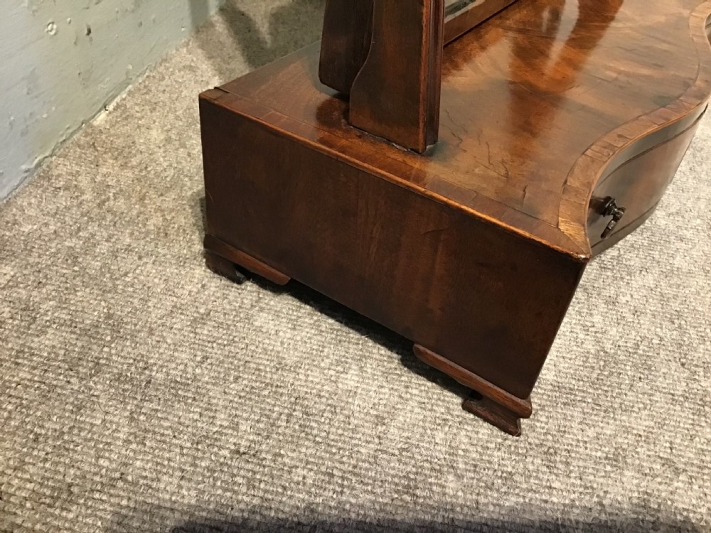 A Georgian mahogany toilet mirror featuring an adjustable glass plate set within vertical posts above a serpentine box base with drawers. View III