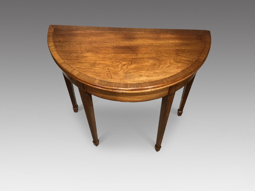 A semi-circular antique mahogany demi-lune table with inlaid apron borders and four tapered square legs. View II