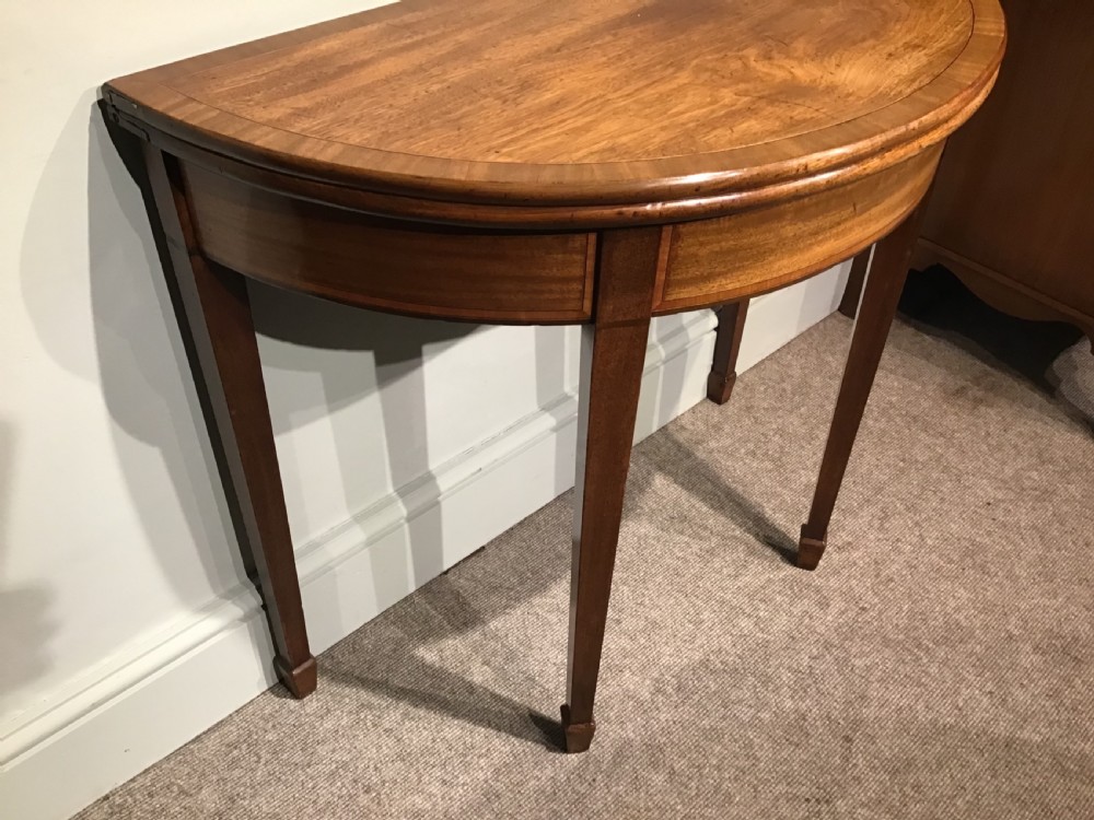 A semi-circular antique mahogany demi-lune table with inlaid apron borders and four tapered square legs. View III