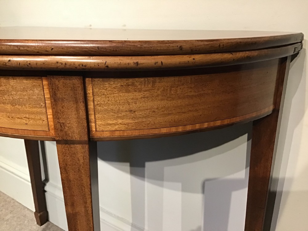 A semi-circular antique mahogany demi-lune table with inlaid apron borders and four tapered square legs. View IV