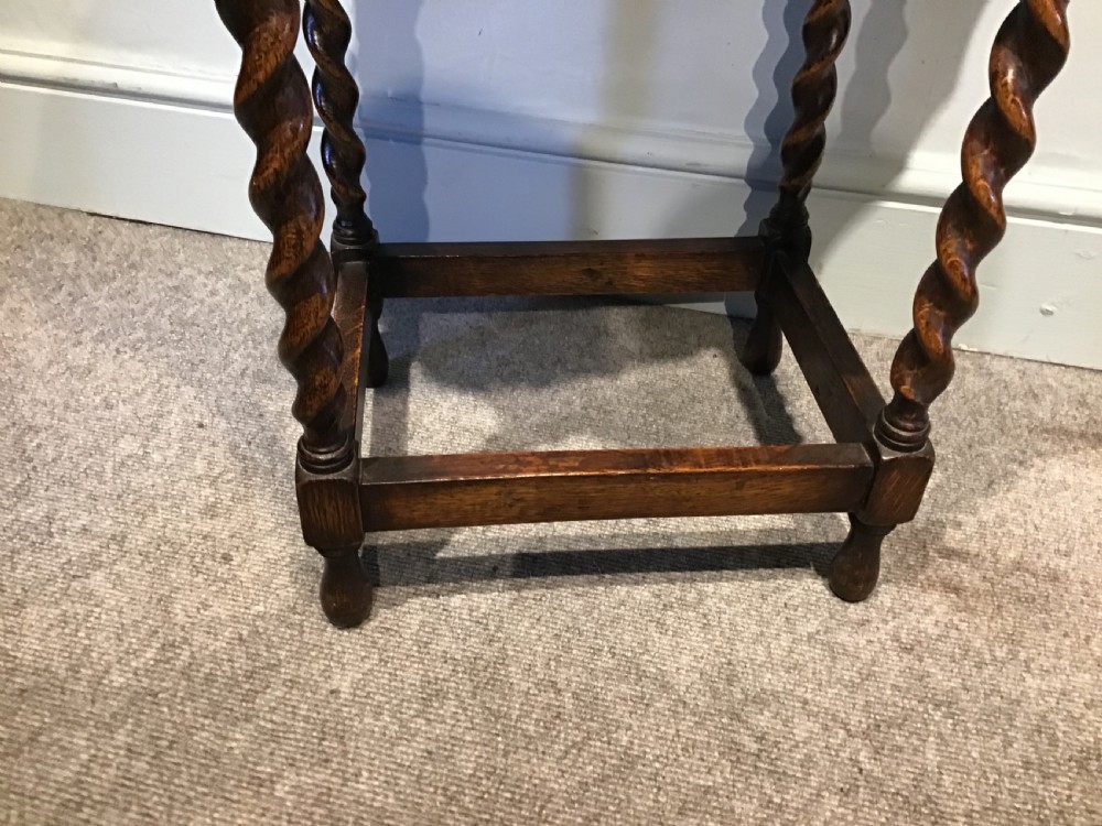 An antique oak occasional table featuring a scalloped piecrust oval top, four spiral barley twist legs, and a lower box stretcher. View III