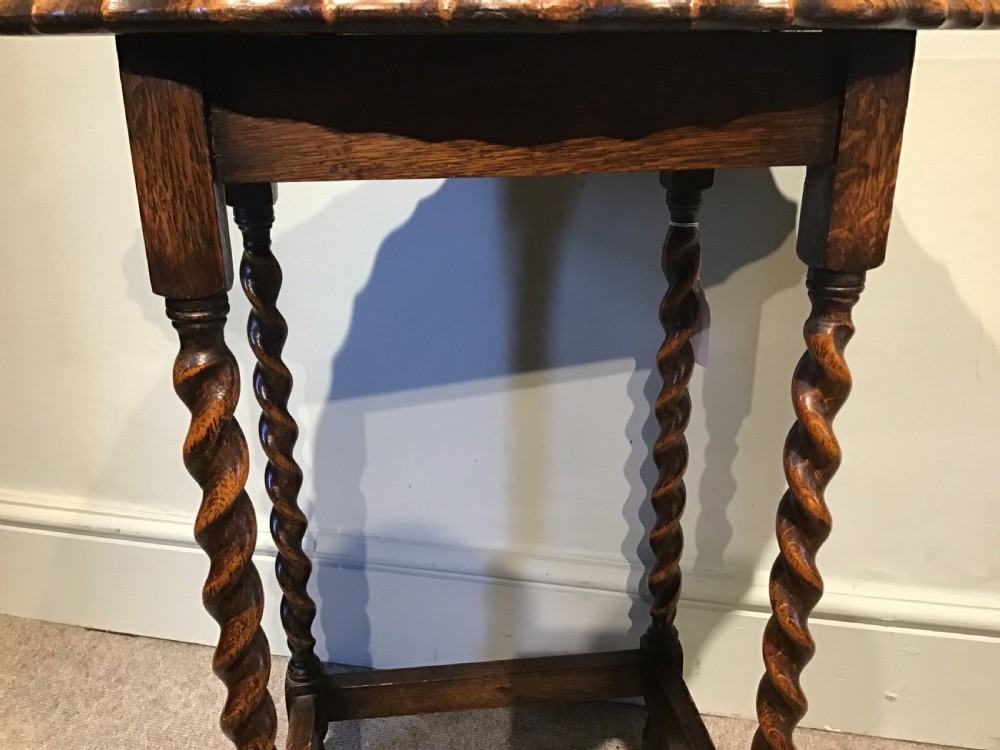 An antique oak occasional table featuring a scalloped piecrust oval top, four spiral barley twist legs, and a lower box stretcher. View IV