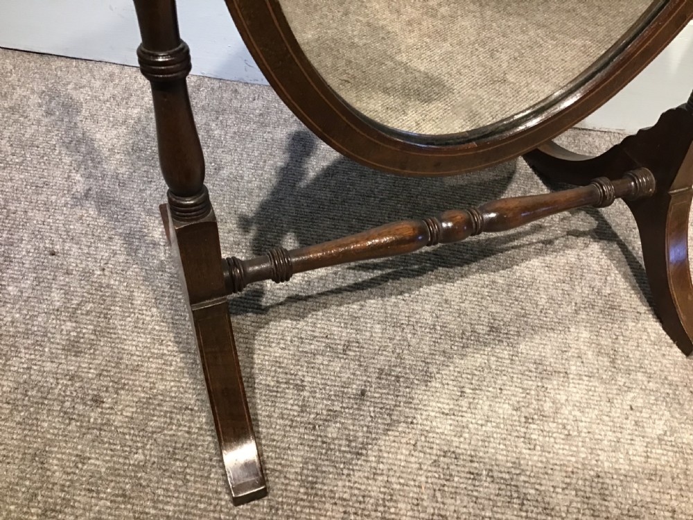 An antique oval toilet mirror crafted from dark polished wood with turned side supports and a stretcher base. View III