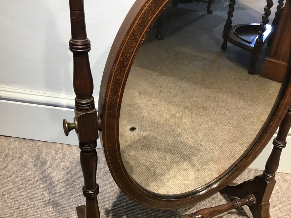 An antique oval toilet mirror crafted from dark polished wood with turned side supports and a stretcher base. View IV