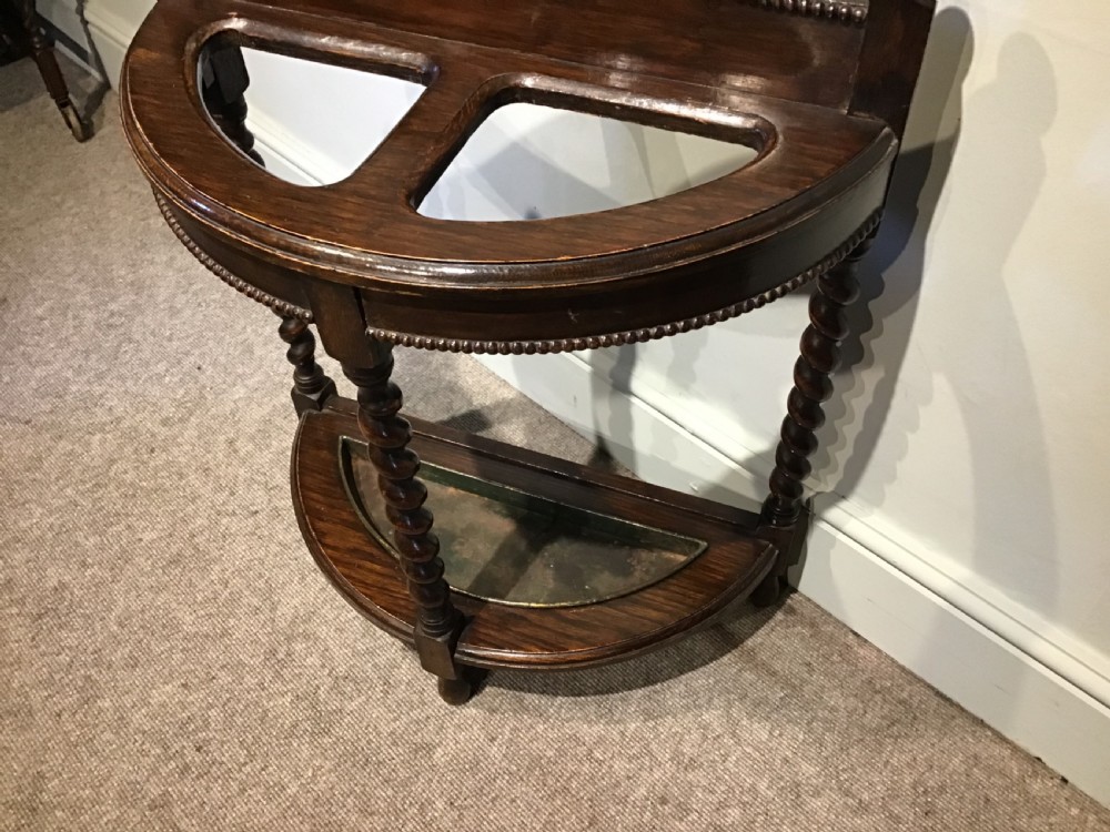 An antique dark oak demilune stick stand featuring three barley twist legs, beaded carved details, two top sections, ball finials, and a fitted metal drip tray. View III