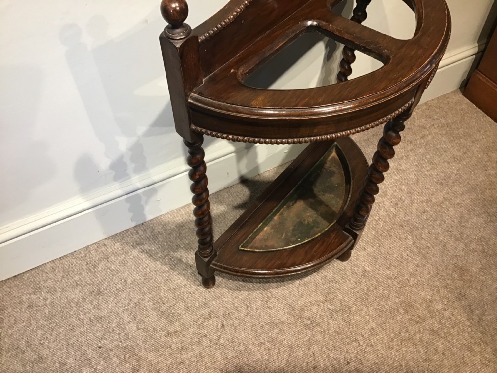 An antique dark oak demilune stick stand featuring three barley twist legs, beaded carved details, two top sections, ball finials, and a fitted metal drip tray. View IV