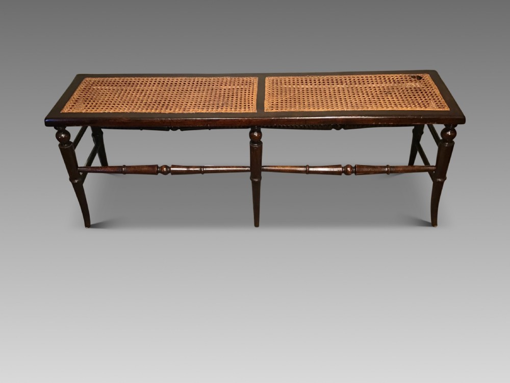 An antique beech and cane long stool