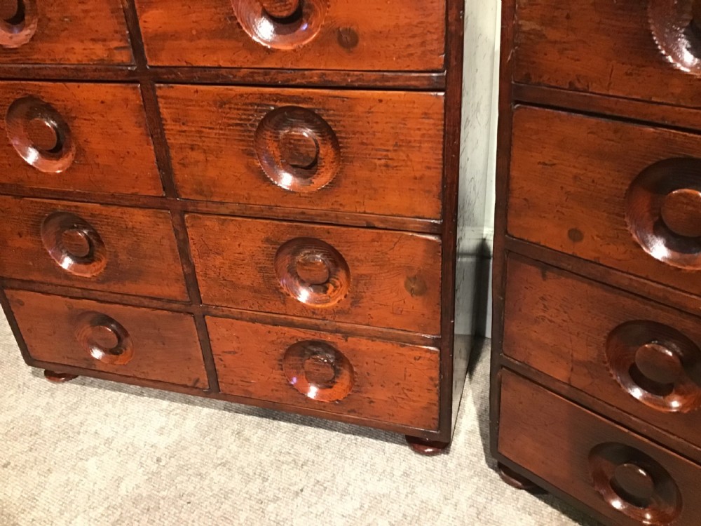 A pair of antique brown wooden apothecary chests, each featuring eight drawers with carved circular recessed handles. View IV