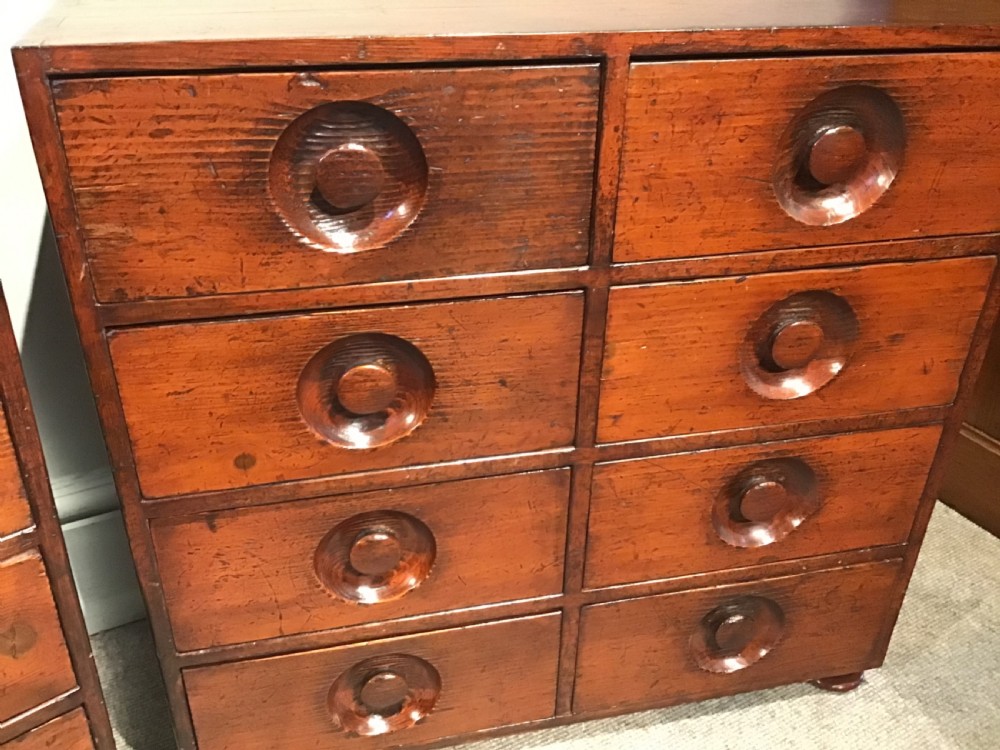 A pair of antique brown wooden apothecary chests, each featuring eight drawers with carved circular recessed handles. View VI