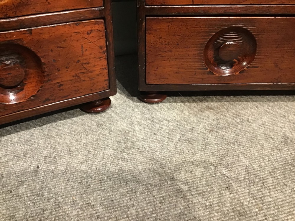 A pair of antique brown wooden apothecary chests, each featuring eight drawers with carved circular recessed handles. View VII