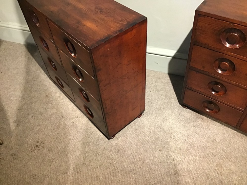 A pair of antique brown wooden apothecary chests, each featuring eight drawers with carved circular recessed handles. View VIII