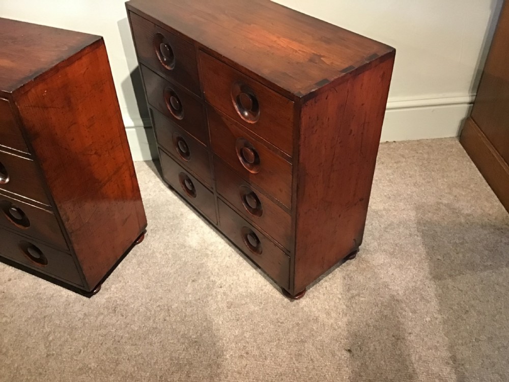 A pair of antique brown wooden apothecary chests, each featuring eight drawers with carved circular recessed handles. View IX