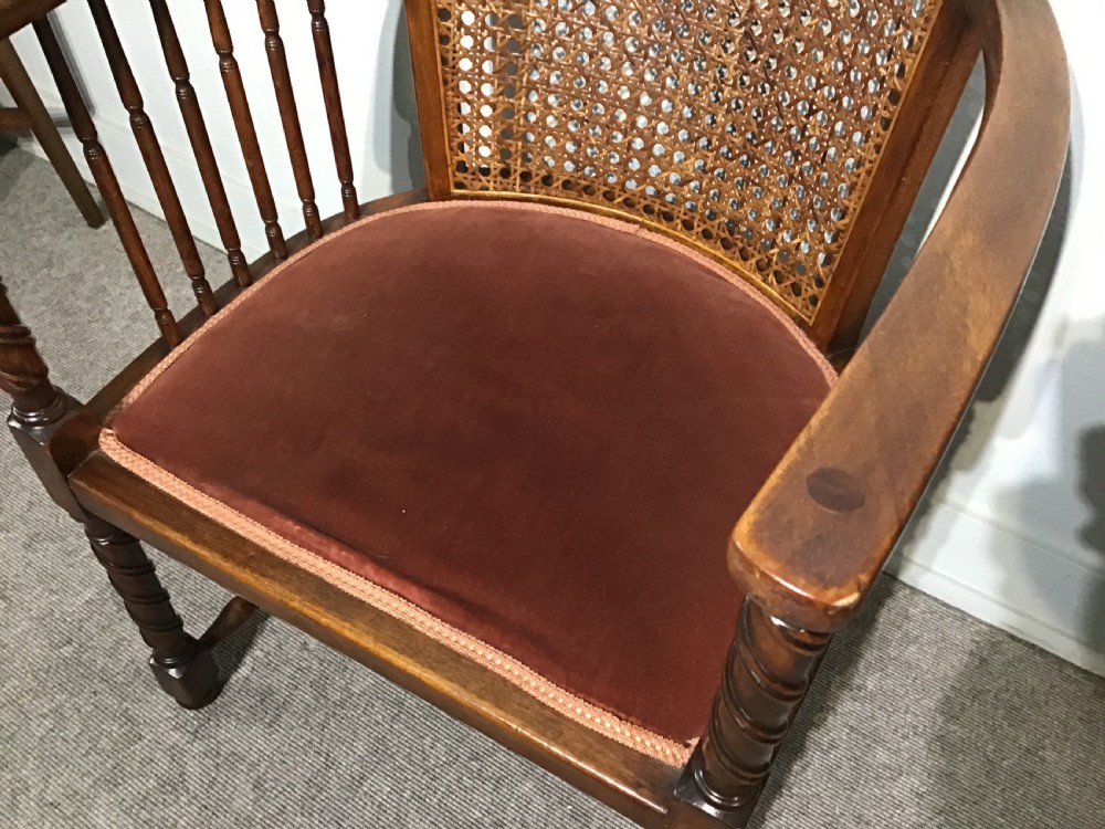 An antique mahogany tub chair featuring a woven cane back panel, turned side spindles, barley twist legs, and a dark brown upholstered seat. View V