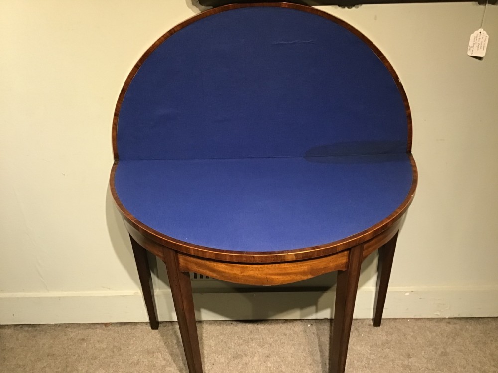 A semi-circular antique mahogany demi-lune card table featuring four square tapered legs and a patterned flame mahogany veneered top surface. View VIII