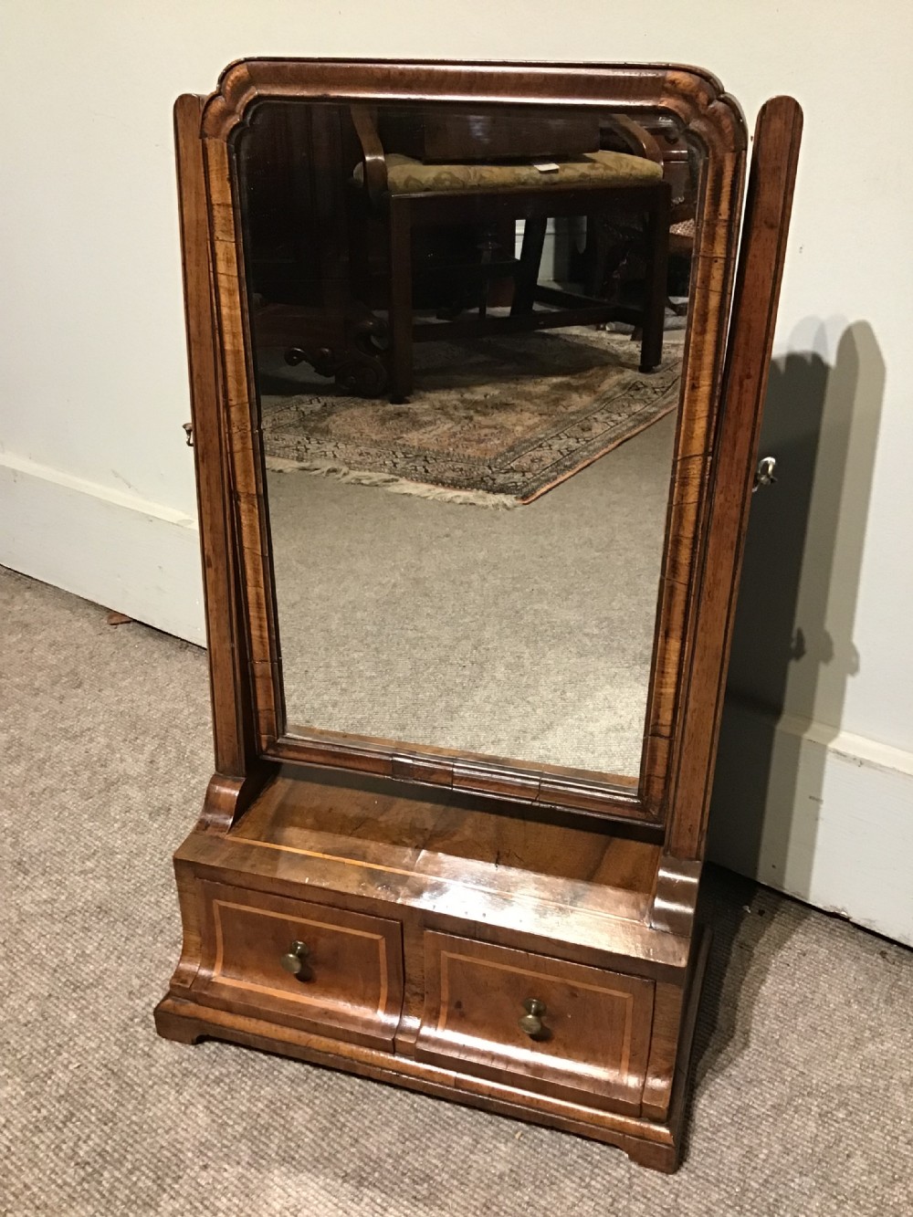 A Georgian walnut toilet mirror featuring a rectangular tilting glass frame supported by upright posts over a base with two small drawers and brass knobs. View II