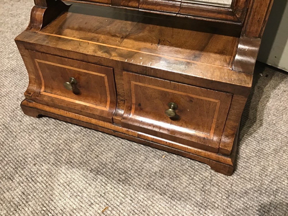 A Georgian walnut toilet mirror featuring a rectangular tilting glass frame supported by upright posts over a base with two small drawers and brass knobs. View III