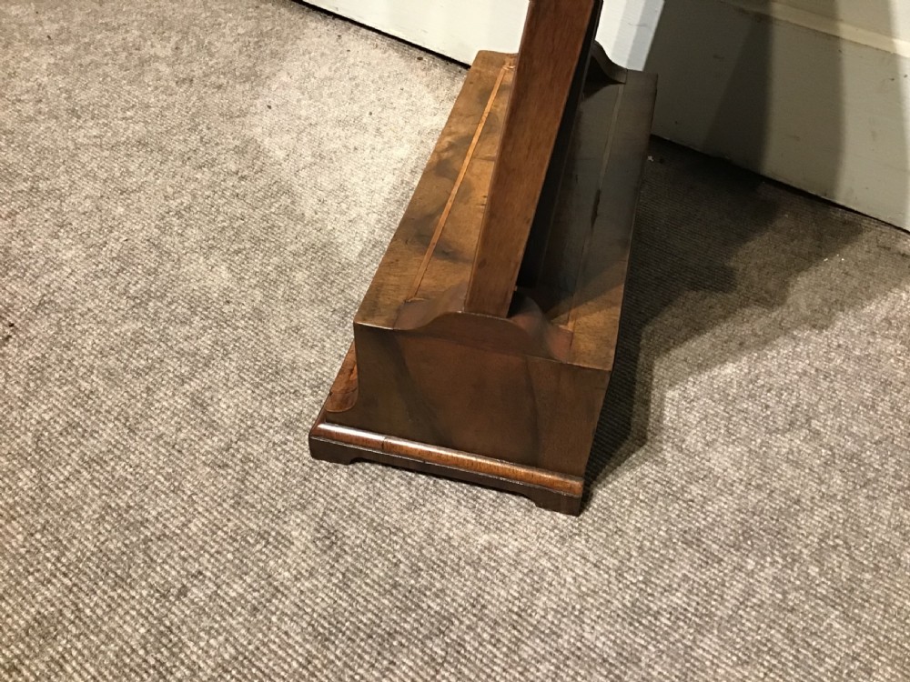 A Georgian walnut toilet mirror featuring a rectangular tilting glass frame supported by upright posts over a base with two small drawers and brass knobs. View VI