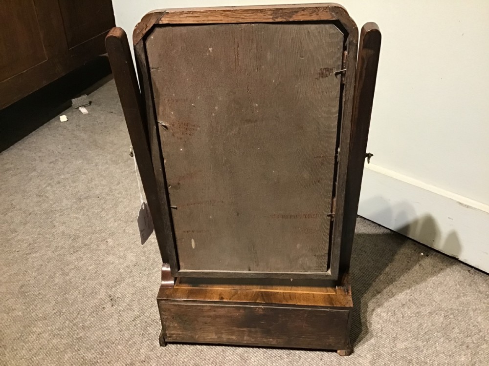 A Georgian walnut toilet mirror featuring a rectangular tilting glass frame supported by upright posts over a base with two small drawers and brass knobs. View VII