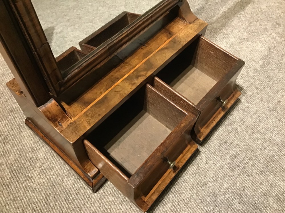 A Georgian walnut toilet mirror featuring a rectangular tilting glass frame supported by upright posts over a base with two small drawers and brass knobs. View VIII