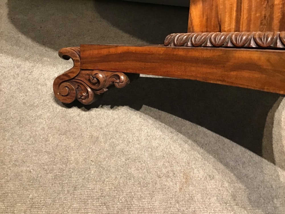 A circular William IV Goncalo Alves tilt-top centre table tilted vertically to show the figured timber grain above a triform base with carved scroll feet. View V