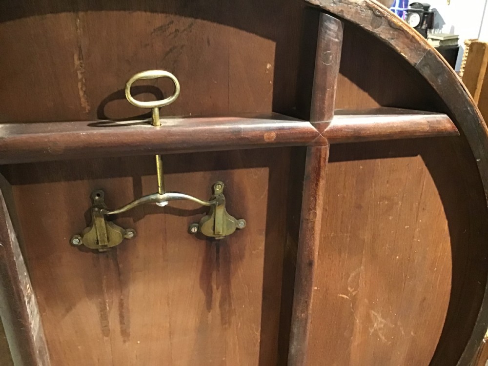 A circular William IV Goncalo Alves tilt-top centre table tilted vertically to show the figured timber grain above a triform base with carved scroll feet. View XI