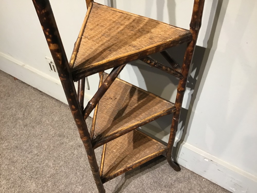 A three-tiered Victorian corner stand crafted from mottled brown bamboo with triangular woven rattan shelves. View III