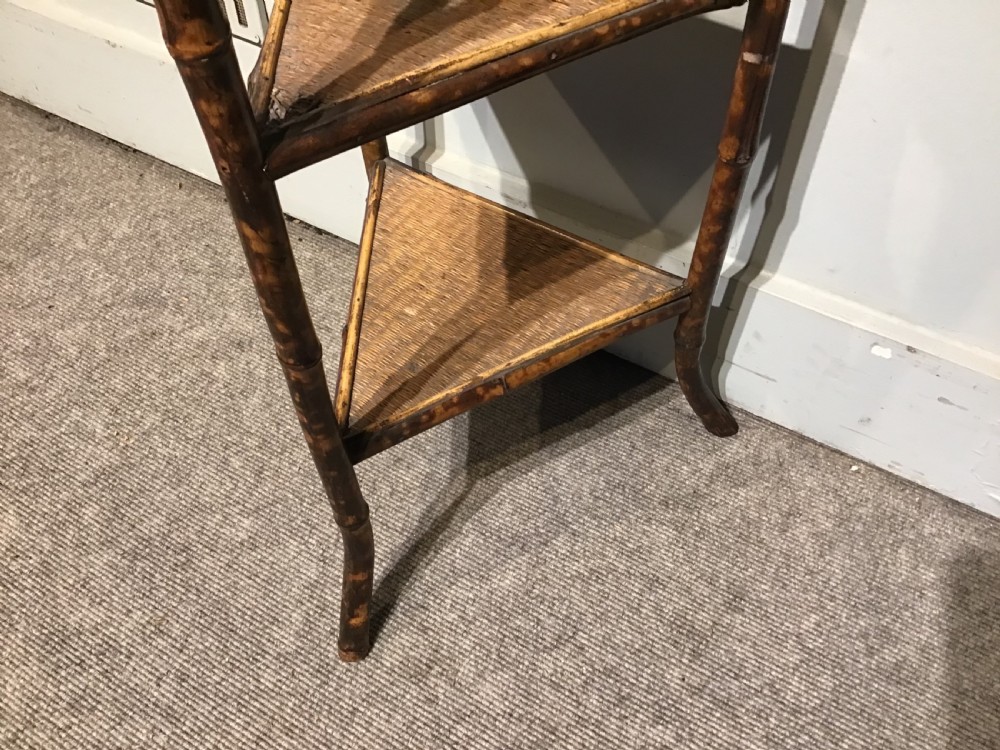 A three-tiered Victorian corner stand crafted from mottled brown bamboo with triangular woven rattan shelves. View IV