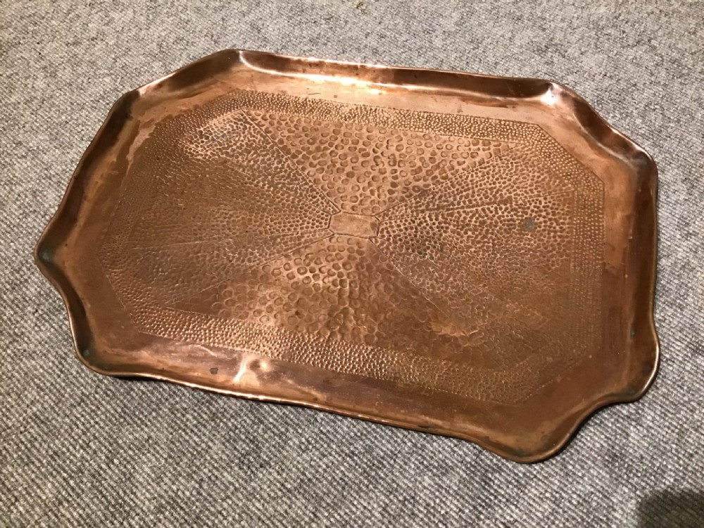 A rectangular Arts and Crafts hand-hammered copper tray featuring a raised scalloped rim and geometric textured surface patterns.