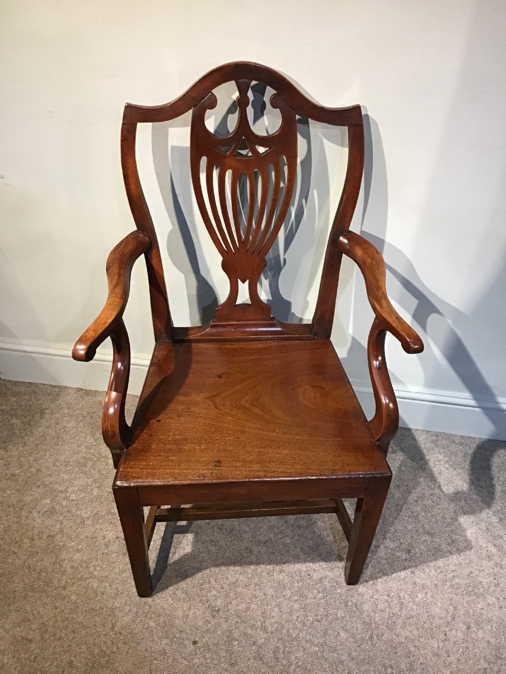 A Georgian mahogany elbow chair featuring a pierced urn-shaped splat back, swept open arms, and square legs supported by H-stretchers. View II