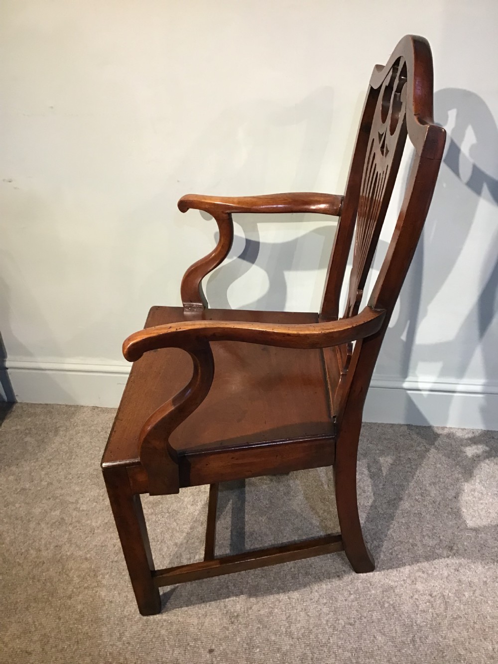 A Georgian mahogany elbow chair featuring a pierced urn-shaped splat back, swept open arms, and square legs supported by H-stretchers. View III