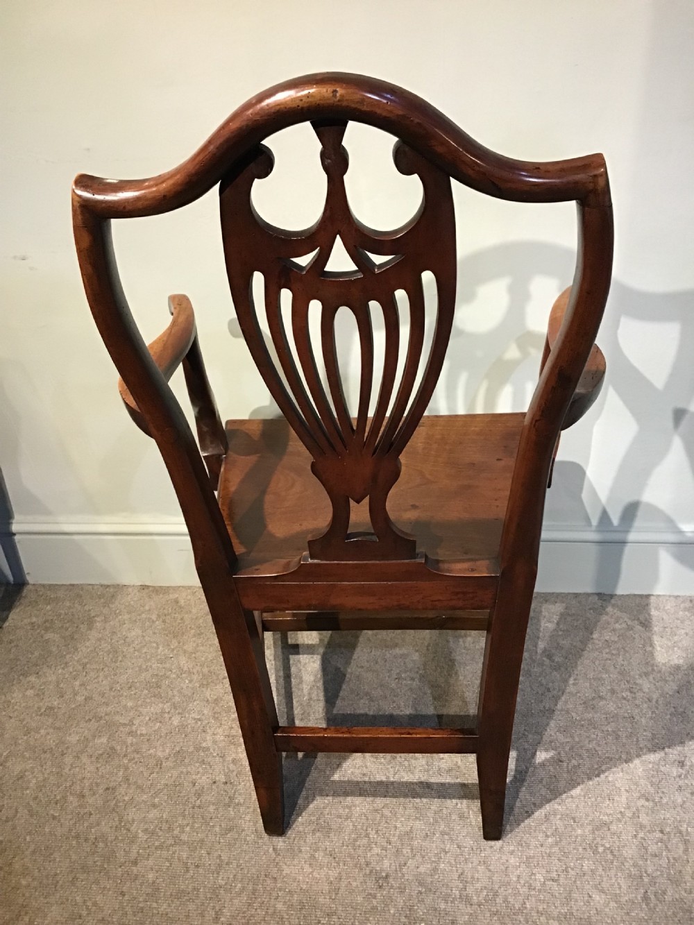A Georgian mahogany elbow chair featuring a pierced urn-shaped splat back, swept open arms, and square legs supported by H-stretchers. View IV