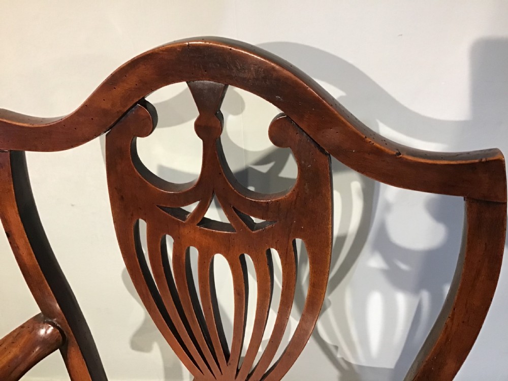 A Georgian mahogany elbow chair featuring a pierced urn-shaped splat back, swept open arms, and square legs supported by H-stretchers. View V