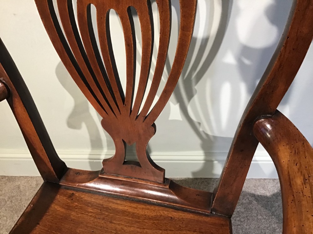 A Georgian mahogany elbow chair featuring a pierced urn-shaped splat back, swept open arms, and square legs supported by H-stretchers. View VI