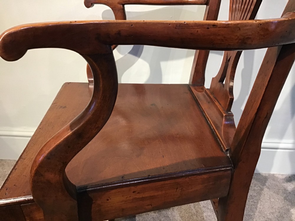 A Georgian mahogany elbow chair featuring a pierced urn-shaped splat back, swept open arms, and square legs supported by H-stretchers. View IX