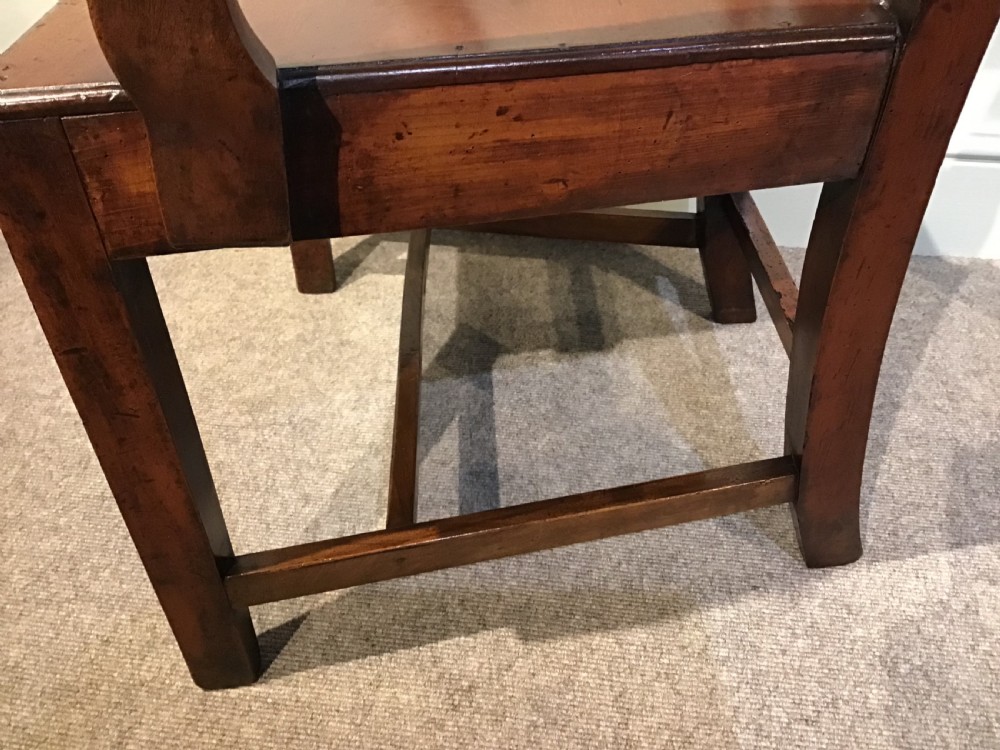 A Georgian mahogany elbow chair featuring a pierced urn-shaped splat back, swept open arms, and square legs supported by H-stretchers. View X