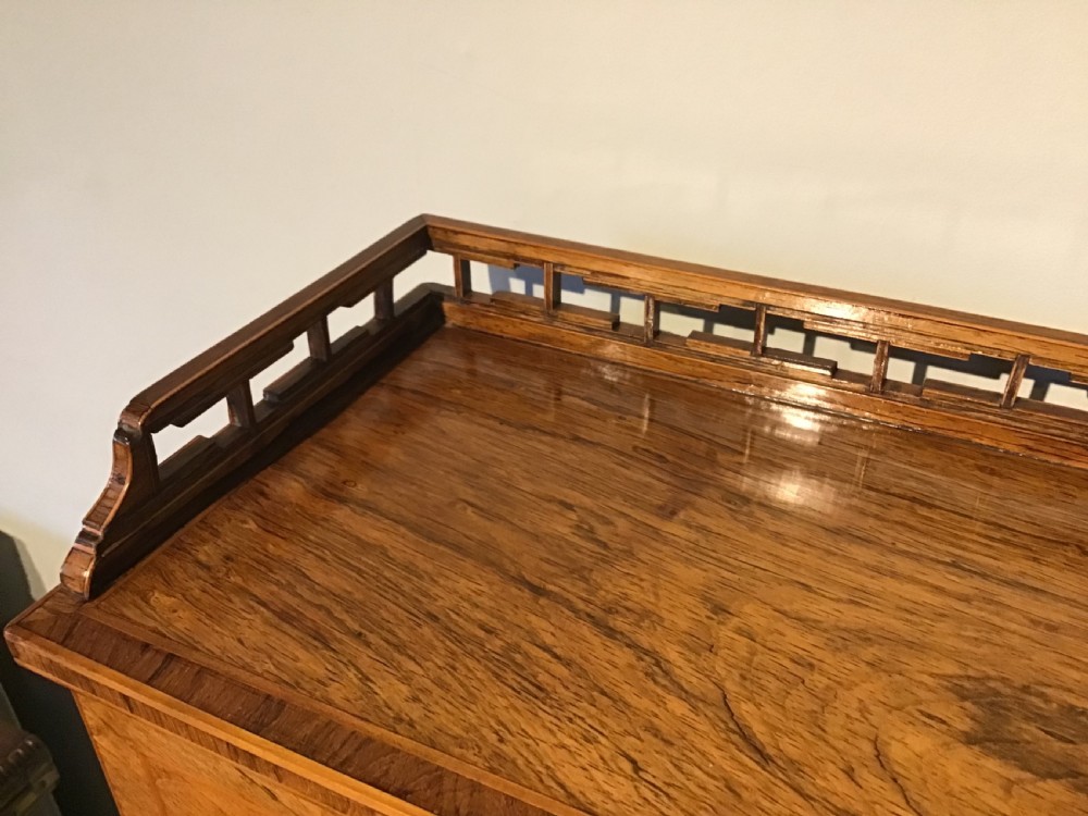 A rosewood bonheur du jour writing desk featuring geometric parquetry veneers, square tapered legs, a frieze drawer, and a raised cabinet top with brass fretwork rail. View V