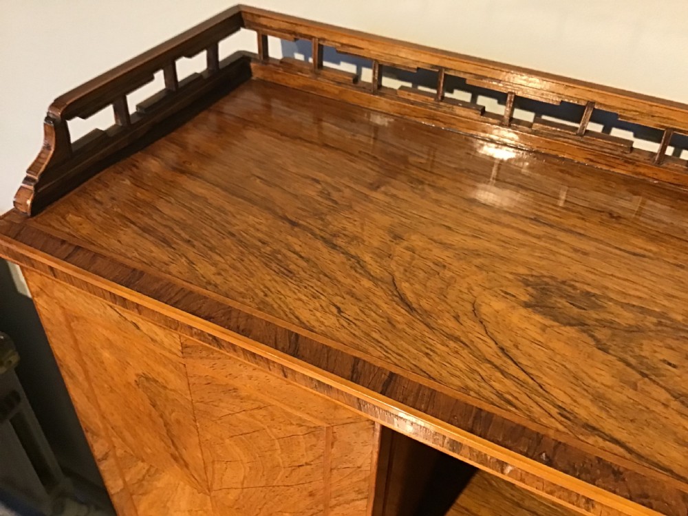A rosewood bonheur du jour writing desk featuring geometric parquetry veneers, square tapered legs, a frieze drawer, and a raised cabinet top with brass fretwork rail. View VI