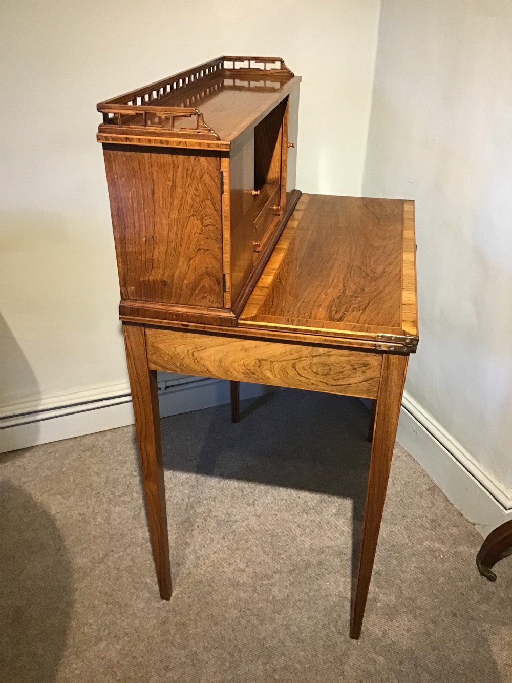 A rosewood bonheur du jour writing desk featuring geometric parquetry veneers, square tapered legs, a frieze drawer, and a raised cabinet top with brass fretwork rail. View XIII