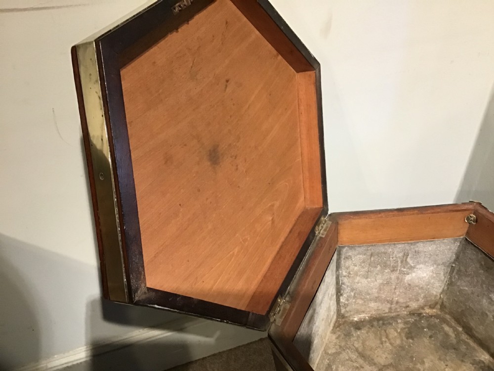 A hexagonal dark mahogany Georgian wine cooler featuring brass binding straps, side handles, and tapered legs on brass castors. View V