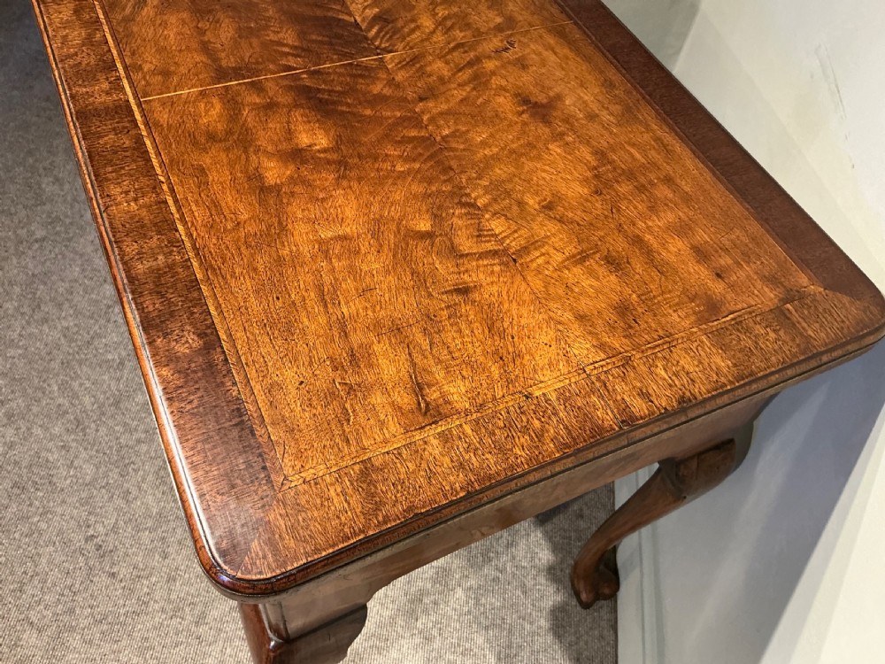 A Georgian walnut lowboy featuring three drawers with brass handles, a crossbanded veneered top, a shaped apron, and four cabriole legs with pad feet. View VII