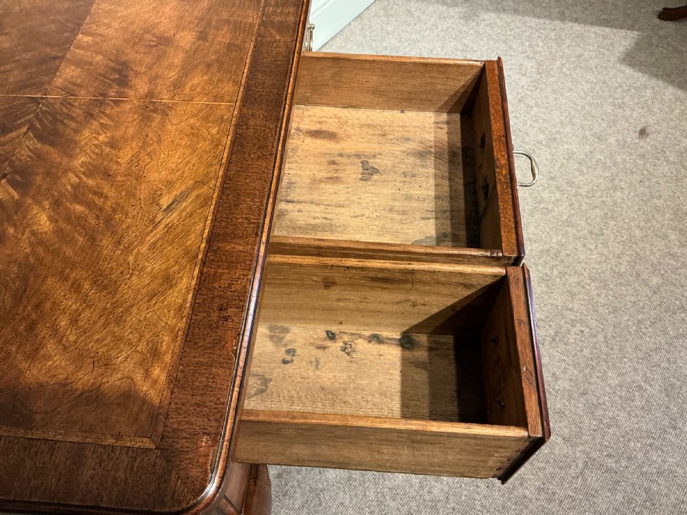 A Georgian walnut lowboy featuring three drawers with brass handles, a crossbanded veneered top, a shaped apron, and four cabriole legs with pad feet. View IX