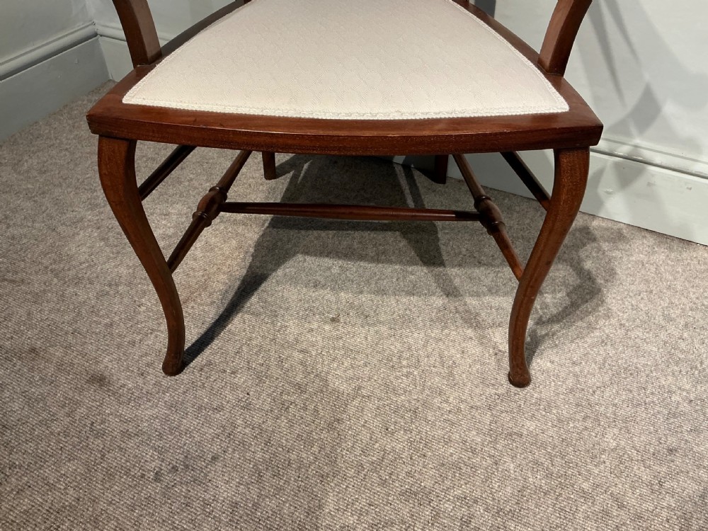 An Edwardian mahogany elbow chair featuring a cream upholstered seat and upper back panel, inlaid vertical splats, curved arms, and cabriole front legs. View III