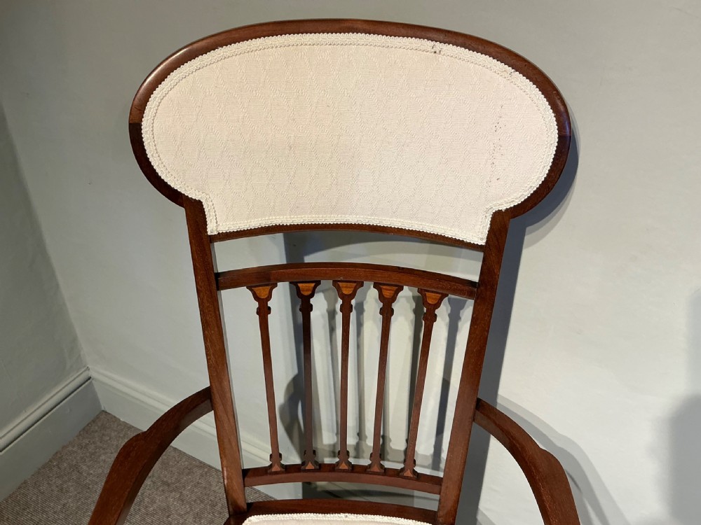 An Edwardian mahogany elbow chair featuring a cream upholstered seat and upper back panel, inlaid vertical splats, curved arms, and cabriole front legs. View V